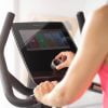 hometrainer B5s van Flow Fitness met 10,1 touchscreen bediend door een vrouw