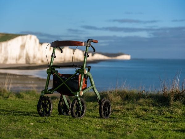 De Trive All Terrain rollator van Uplivin staat in een natuurlijke omgeving met uitzicht op zee. Deze rollator is ontworpen voor vrijheid en vertrouwen, ideaal voor wandelingen op zowel verharde als onverharde paden.