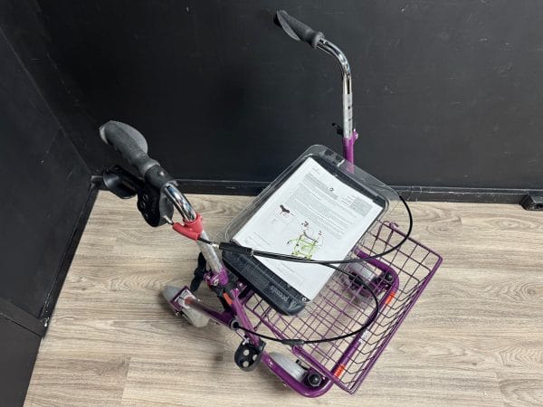 Premis Provo rollator paars, schuin-bovenaanzicht, met eenzijdige rem rechts en mand met handleiding onder het stuur.