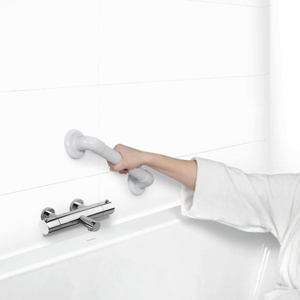 Wandbeugel Vitility voor douche en toilet, zijaanzicht: hand grijpt geribbelde antislip greep op witte tegelwand.