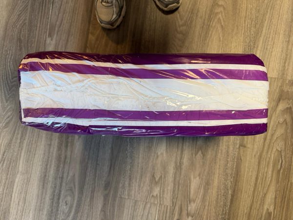 Pak Absorin Comfort Slip Day/Night Large met gescheurde onderkant van de paarse verpakking op houten vloer