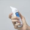 Hand holding an OMRON Gentle Temp 533 infrared oorthermometer with display showing 38.0 °C