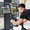 Man traint thuis op de VirtuFit ETAPPE 2.0i indoor cycle bike met tablet en interactieve trainingsapps voor virtuele routes en weerstandsregeling.