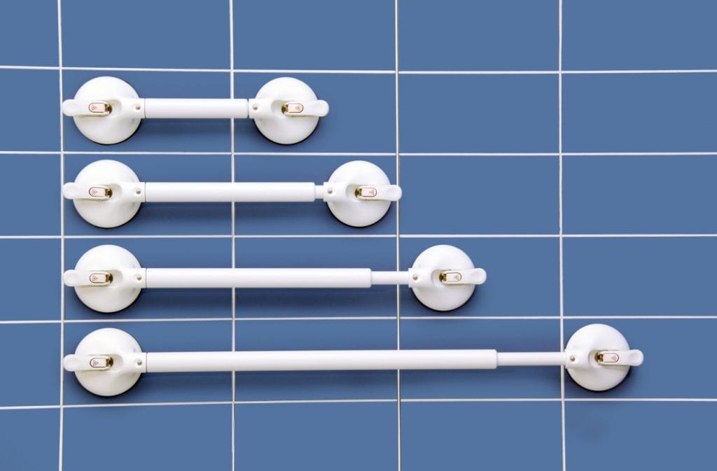 Mobeli verstelbare wandbeugel met zuignap in vier lengtes op blauwe badkamertegelwand voor extra steun bij toilet en douche.