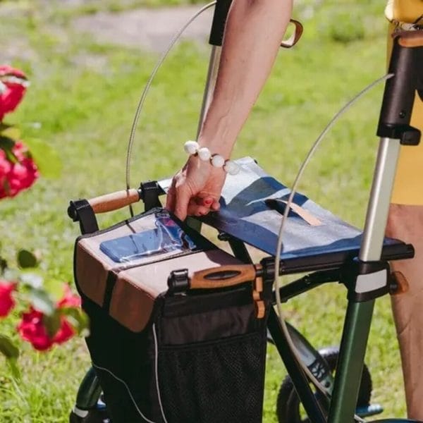 Saljol Carbon rollator Wide in groen met tas en kurkhandvatten, gebruikt buiten in de tuin.