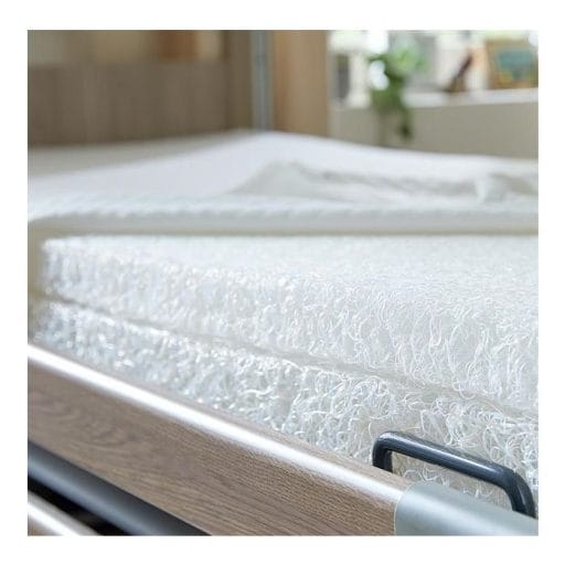 Matras SOOF duurzaam zorgmatras met witte open 3D-vezelstructuur op hoog laag bed, detail van ventilerende kern.