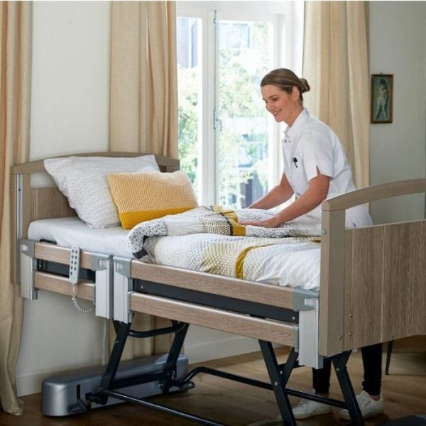 Zorgmedewerker maakt een hoog-laagbed op met het duurzame Matras SOOF, in een lichte slaapkamer met geel-witte dekens.