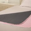 Vida matrasbeschermer met instopstroken in roze en grijs op bed, wasbaar en absorberend tot maximaal 3 liter