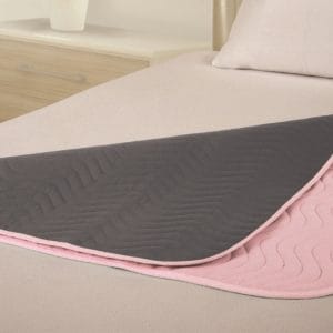 Vida matrasbeschermer met instopstroken in roze en grijs op bed, wasbaar en absorberend tot maximaal 3 liter