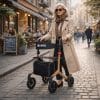 Vrouw met zonnebril loopt met een lichtgewicht rollator met panterprint, tas en rugsteun door een stadsstraat.