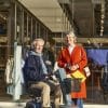 Man op de EON scootmobiel naast een vrouw met winkeltassen voor een winkelpand