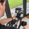 Man bedient de zwarte Flow Fitness Perform S2i spinningfiets met tablet waarop de Kinomap-app een virtuele fietsroute toont