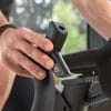 Zwarte Flow Fitness Perform S2i spinningfiets met hand aan de instelhendel tijdens het aanpassen van de weerstand